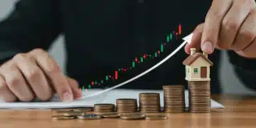 Hand placing model house on coins with rising interest rate graph